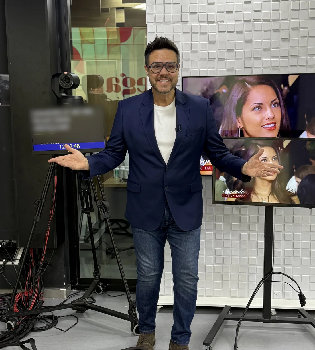 Vinícius Valverde em um estúdio de TV, entre a câmera, o teleprompter e os monitores