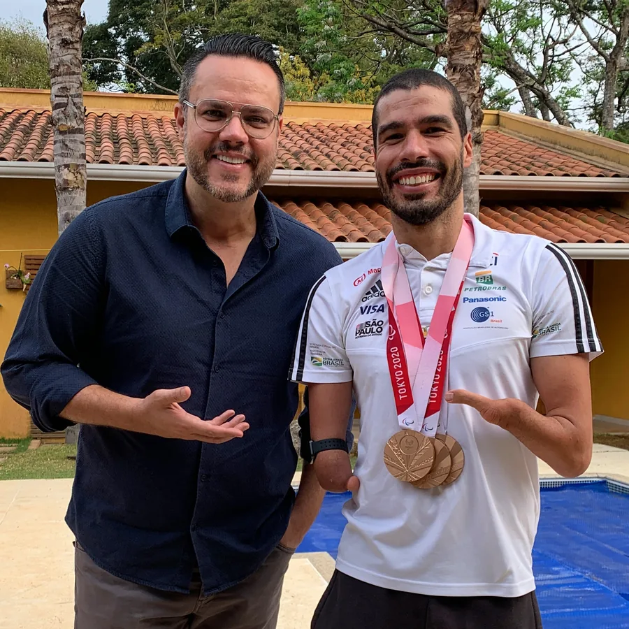 Vinícius Valverde ao lado de um atleta com suas medalhas