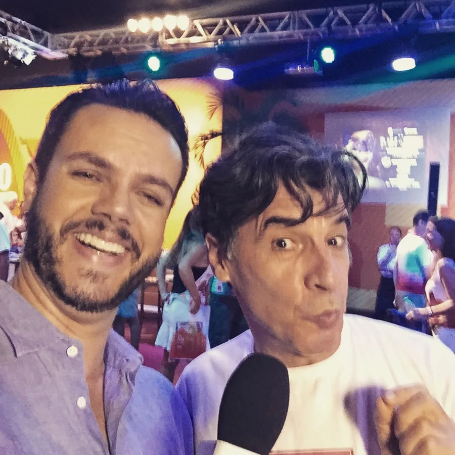 Vinícius Valverde com um convidado que segura o microfone numa festa