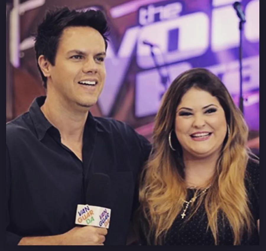 Vinícius Valverde, com microfone, ao lado de uma cantora nos bastidores de um programa